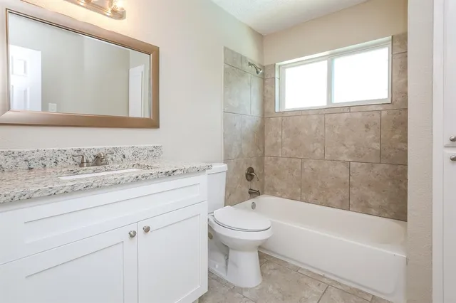 a bathroom with a granite countertop toilet a sink and bathtub