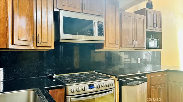 a kitchen with stainless steel appliances granite countertop a stove a sink and a microwave