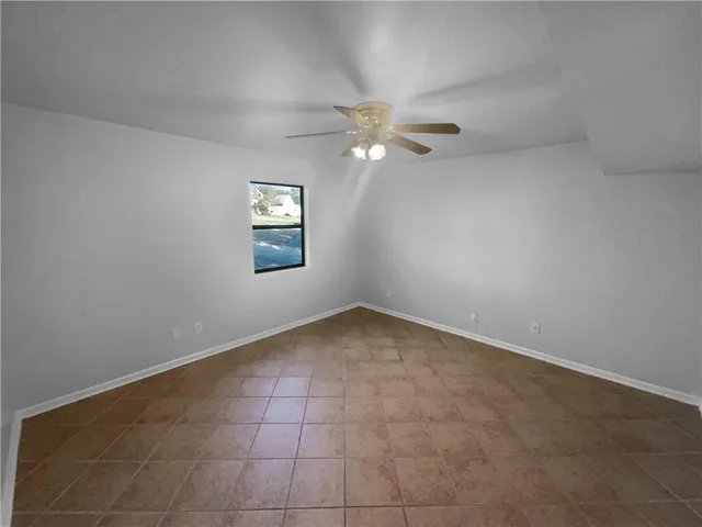 an empty room with a window and ceiling fan