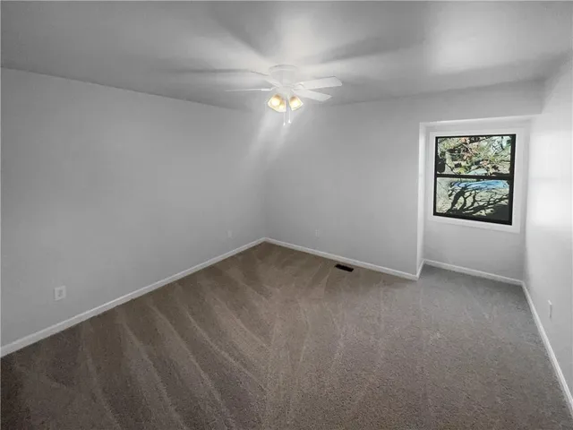 an empty room with a window and ceiling fan