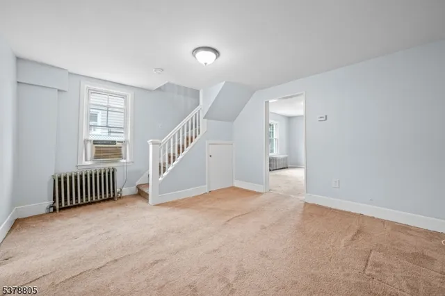 a view of an empty room with stairs and a window