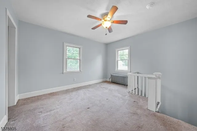 an empty room with windows and ceiling fan