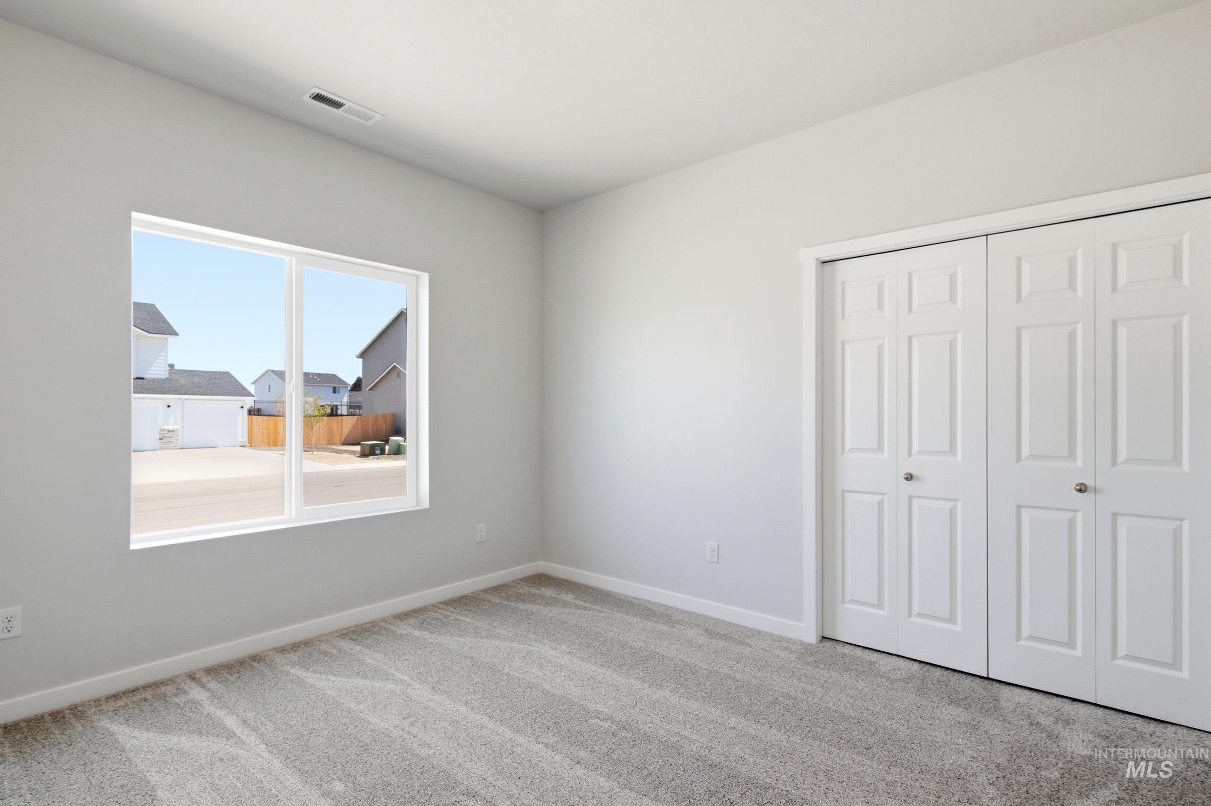 13649 Inman Court Caldwell, ID 83607 - Photo 17 of 22 Window-framed view of surrounding properties, complemented by light gray wall paint and textured gray carpeting