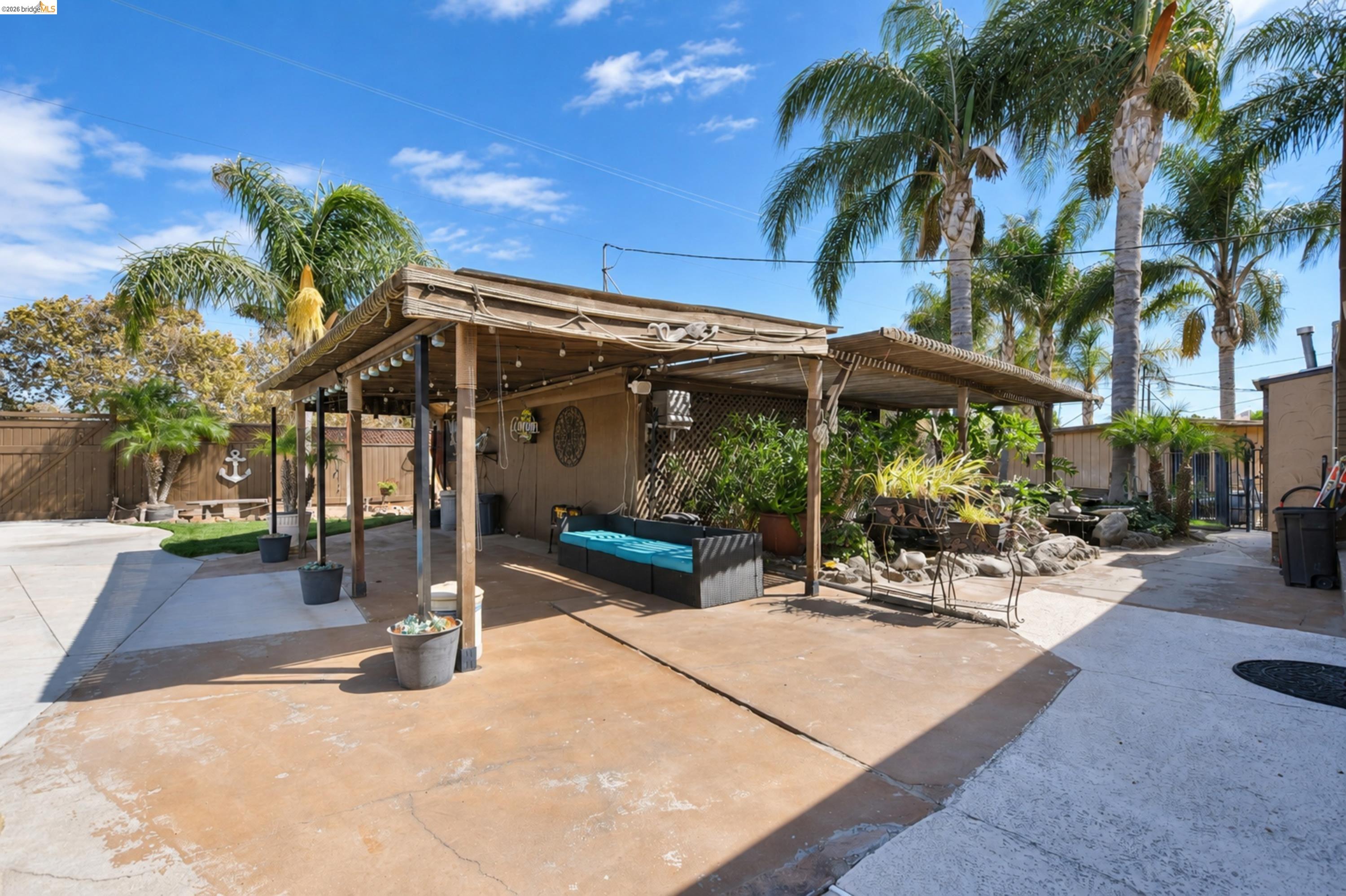 340 West Bolton Road Oakley, CA 94561 - Photo 58 of 87 Expansive concrete patio with a covered pergola, surrounded by mature palm trees and a privacy fence