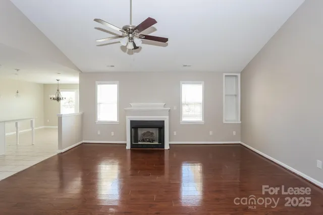 an empty room with wooden floor a fireplace and windows