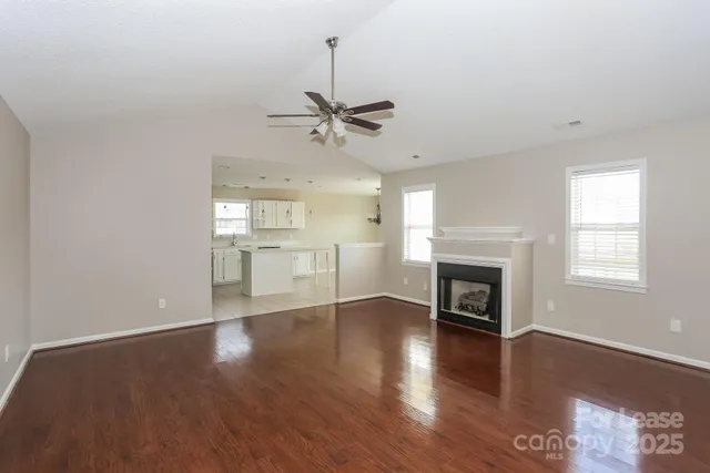 a view of a livingroom with a fireplace a ceiling fan and wooden floor
