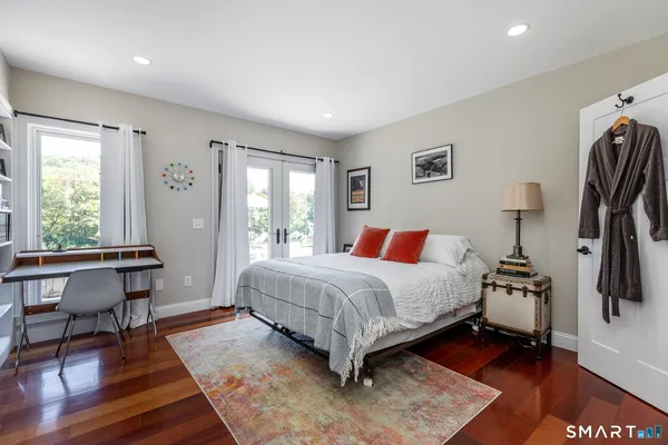 a bedroom with a bed a table and three windows