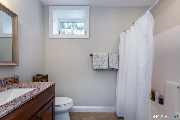 a bathroom with a granite countertop sink toilet and a mirror