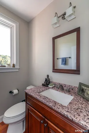 a bathroom with a granite countertop sink a mirror and a toilet
