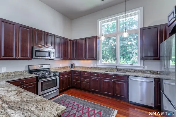 a kitchen with stainless steel appliances granite countertop wooden cabinets a stove a sink and a window