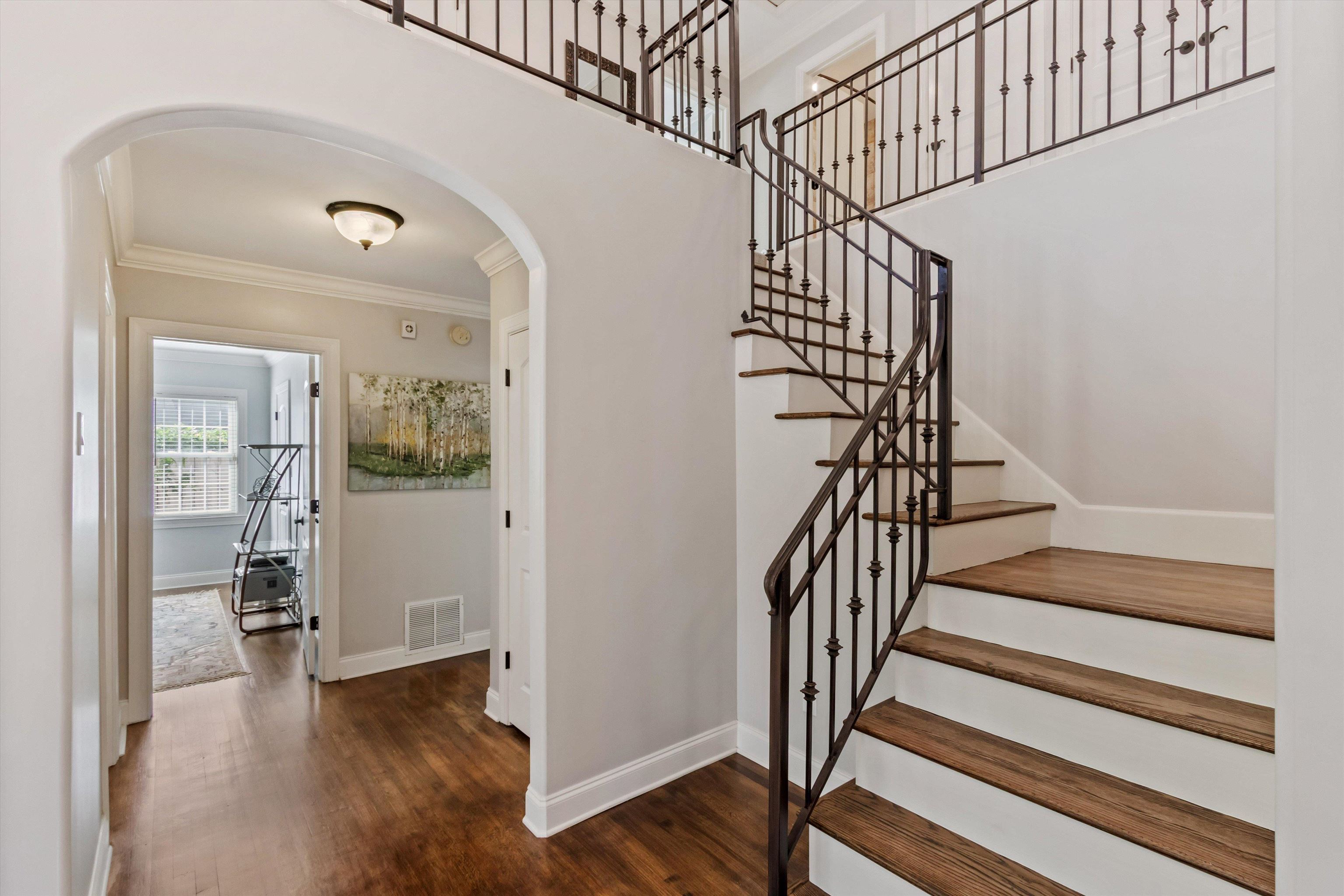 5302 South Angela Road Memphis, TN 38120 - Photo 3 of 40 Grand staircase with dark wood-finish treads and white risers, featuring ornate wrought iron balusters and railing. Reconstructed home in 38120 with 3 bedrooms down and 2 bedrooms plus bonus upstairs.