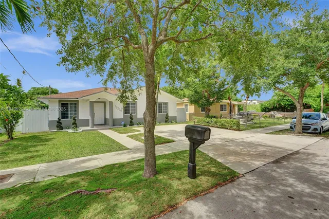 a view of backyard of house with wooden fence and trees