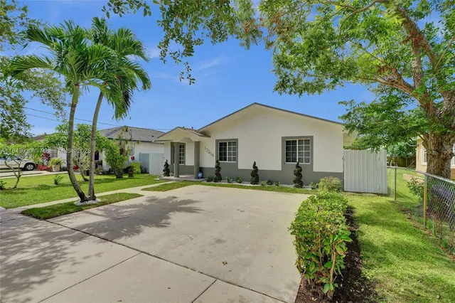 a white house with a big yard and large tree