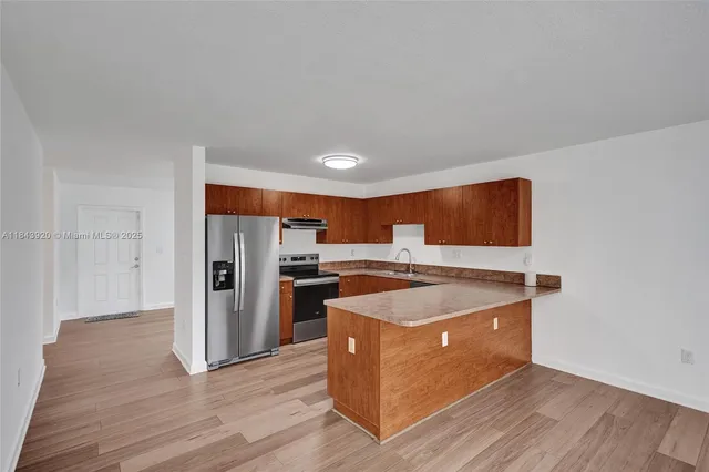 a kitchen with stainless steel appliances granite countertop a stove a refrigerator a sink and dishwasher with wooden floor