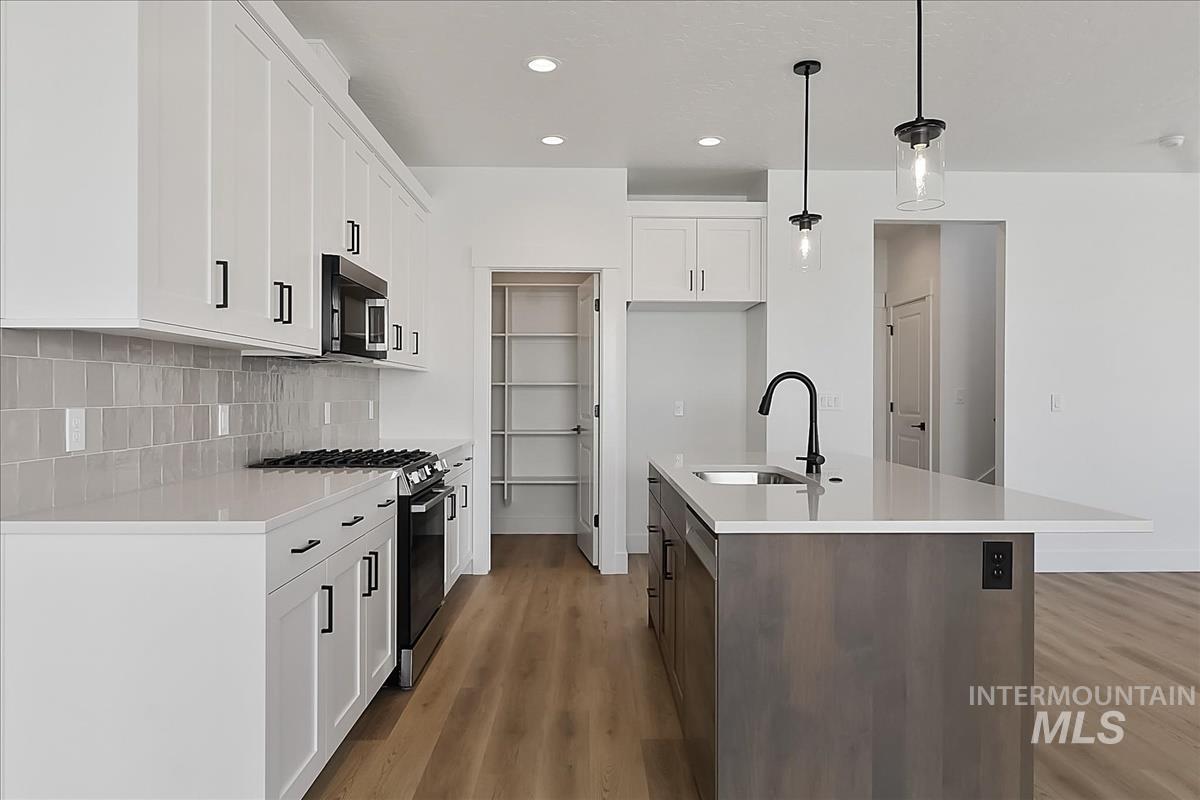 776 South Calhoun Lane Star, ID 83669 - Photo 5 of 49 Contemporary kitchen with white shaker cabinetry, quartz countertops, a gray subway tile backsplash, and wood-finish flooring