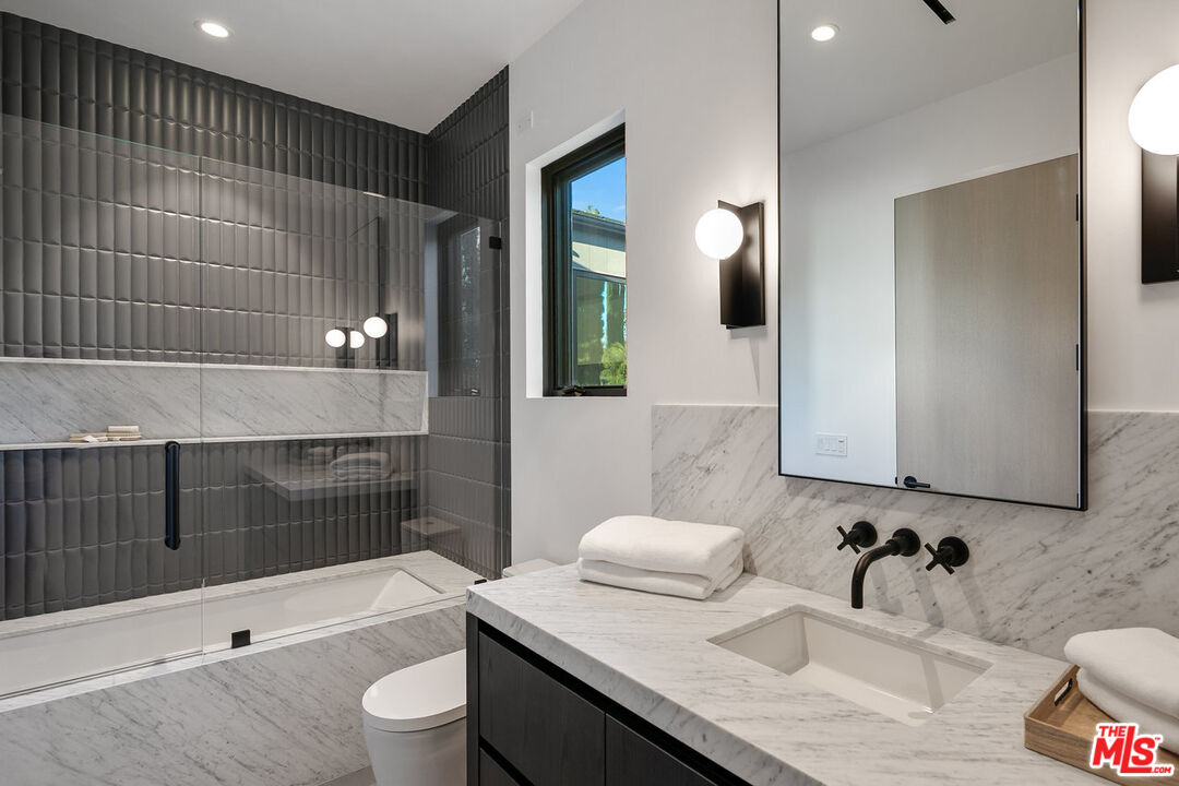 5376 Round Meadow Road Hidden Hills, CA 91302 - Photo 21 of 31 a bathroom with a granite countertop sink a toilet a mirror and shower