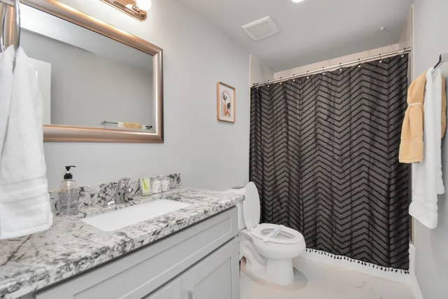 a bathroom with a granite countertop toilet sink and mirror