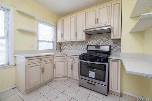a kitchen with granite countertop white cabinets stainless steel appliances and a window