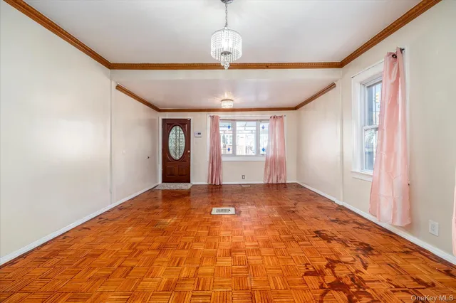 a view of an empty room with window and wooden floor