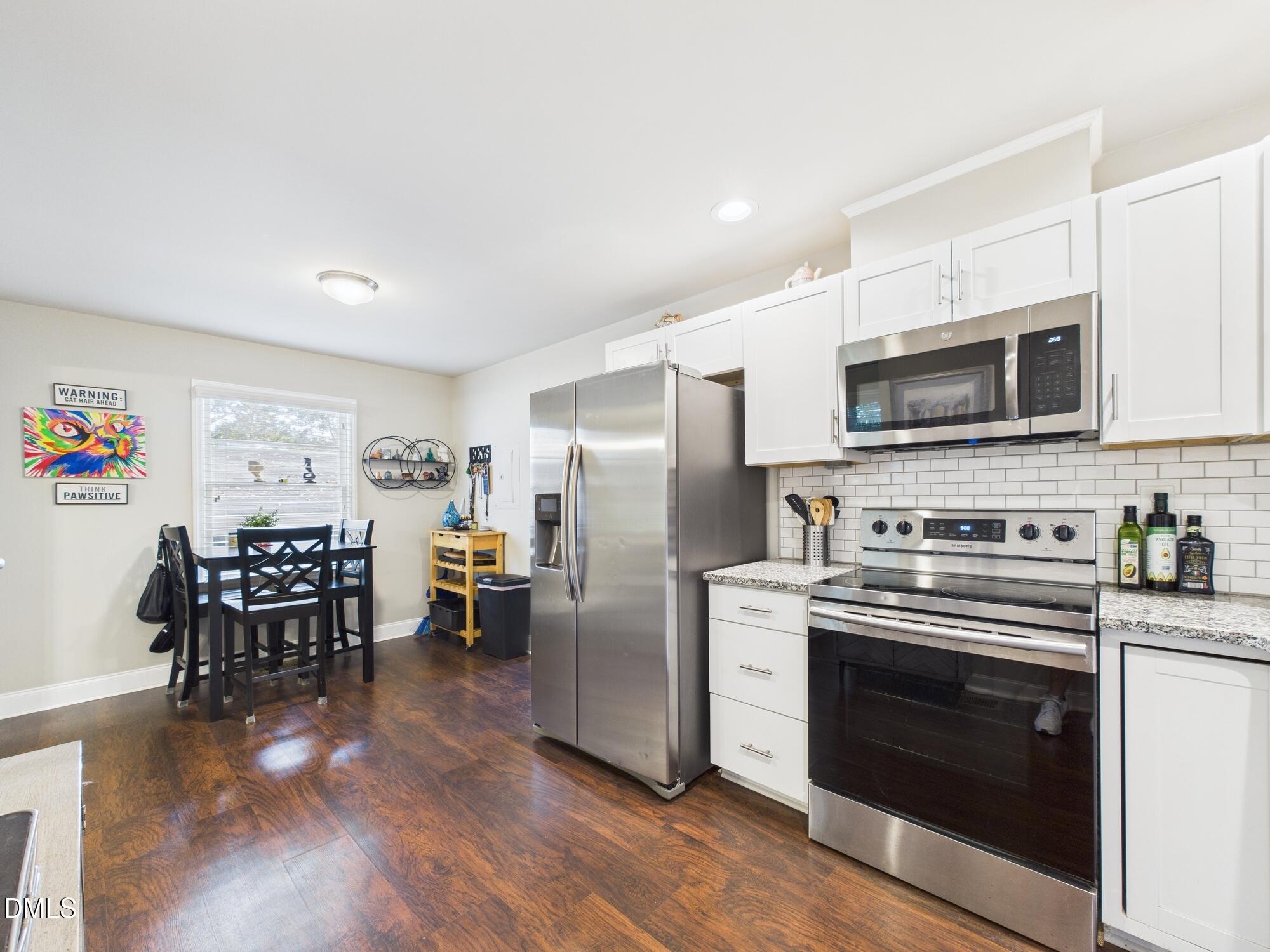 109 Blanchard Street Raleigh, NC 27603 - Photo 17 of 57 a kitchen with stainless steel appliances a stove a sink a refrigerator cabinets and a dining table with wooden floor