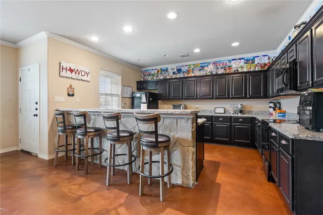 a kitchen with stainless steel appliances granite countertop a stove top oven a sink a dining table and chairs