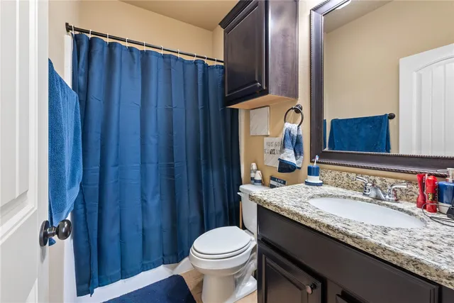 a bathroom with a granite countertop sink toilet and mirror
