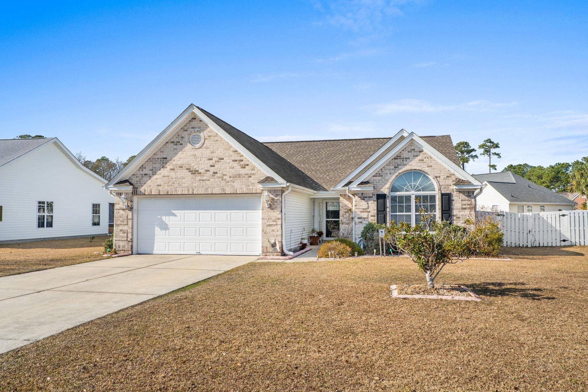 View of front facade featuring brick siding, concrete driveway, an attached garage, and roof with shingles
