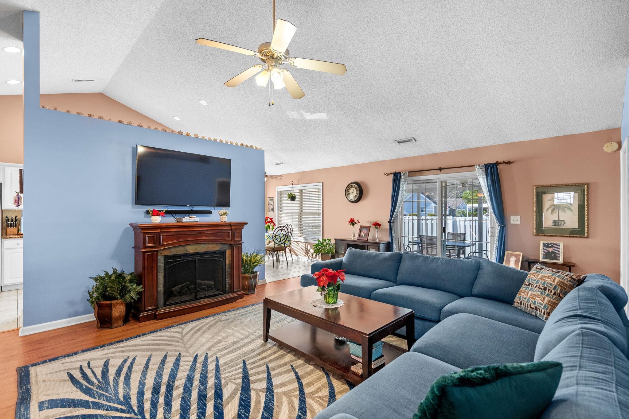 120 Point Break Drive Myrtle Beach, SC 29588 - Photo 12 of 38 Living area with a fireplace with raised hearth, vaulted ceiling, wood finished floors, ceiling fan, and a textured ceiling