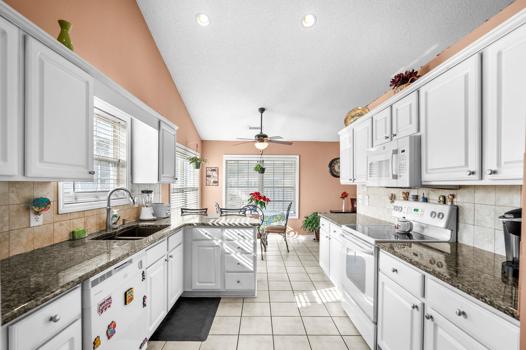 120 Point Break Drive Myrtle Beach, SC 29588 - Photo 20 of 38 Kitchen featuring white appliances, backsplash, dark stone counters, white cabinetry, and lofted ceiling