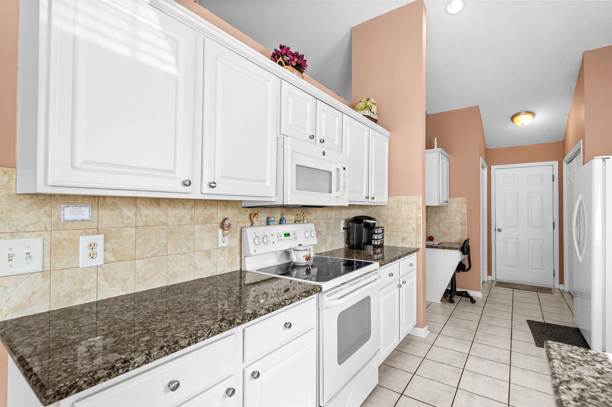 120 Point Break Drive Myrtle Beach, SC 29588 - Photo 21 of 38 Kitchen featuring white appliances, white cabinets, tasteful backsplash, and dark stone countertops