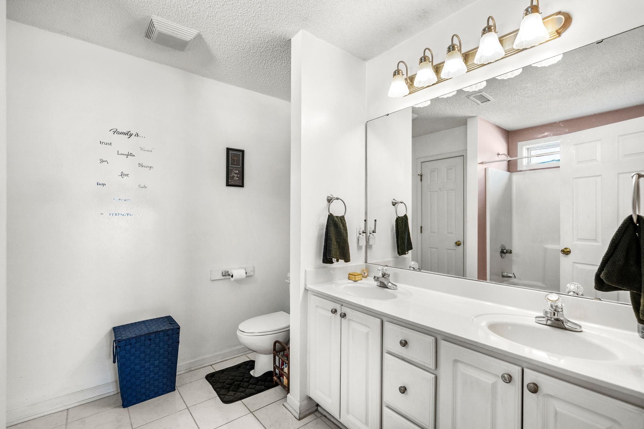 120 Point Break Drive Myrtle Beach, SC 29588 - Photo 27 of 38 Bathroom with a textured ceiling, double vanity, light tile patterned flooring, and washtub / shower combination