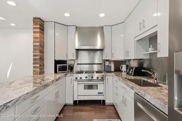 a kitchen with granite countertop a sink stainless steel appliances and cabinets