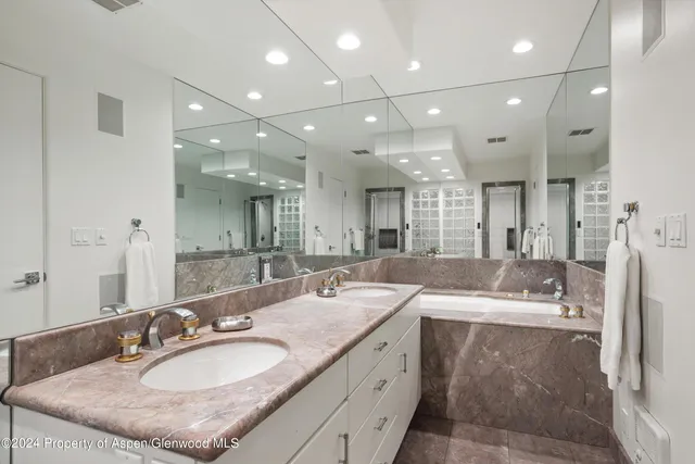 a bathroom with a granite countertop double vanity sink a mirror and a shower