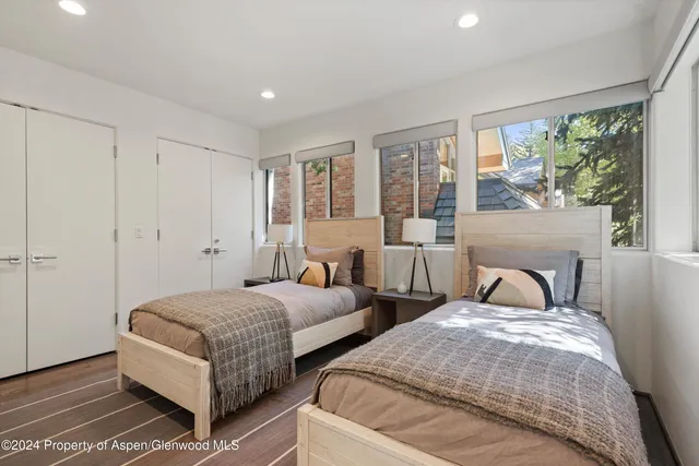 a bedroom with two beds and large windows