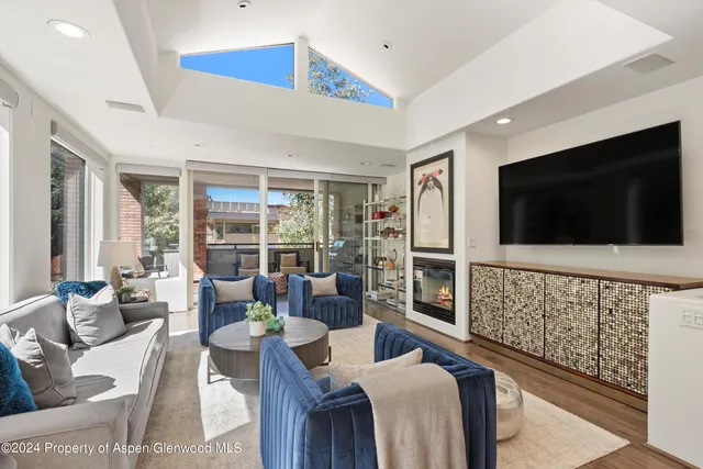 a living room with furniture a flat screen tv a rug and a large window