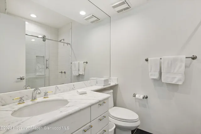 a bathroom with a granite countertop sink a toilet and a mirror