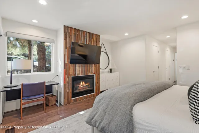 a bedroom with a bed a fireplace and a television