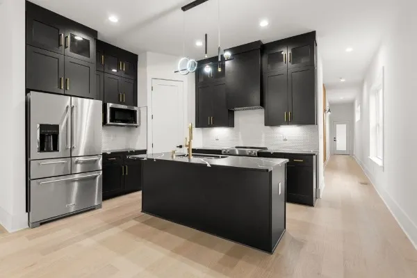 a kitchen with stainless steel appliances granite countertop a sink a stove top oven a refrigerator with island and chairs