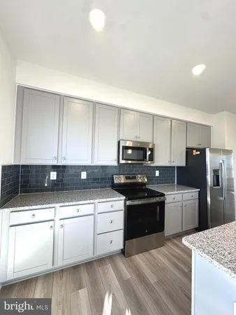 a kitchen with stainless steel appliances kitchen island granite countertop a sink and white cabinets