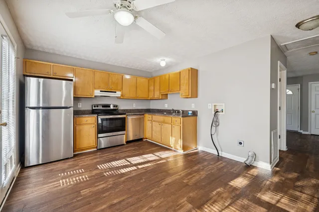 a kitchen with granite countertop a refrigerator cabinets and wooden floor