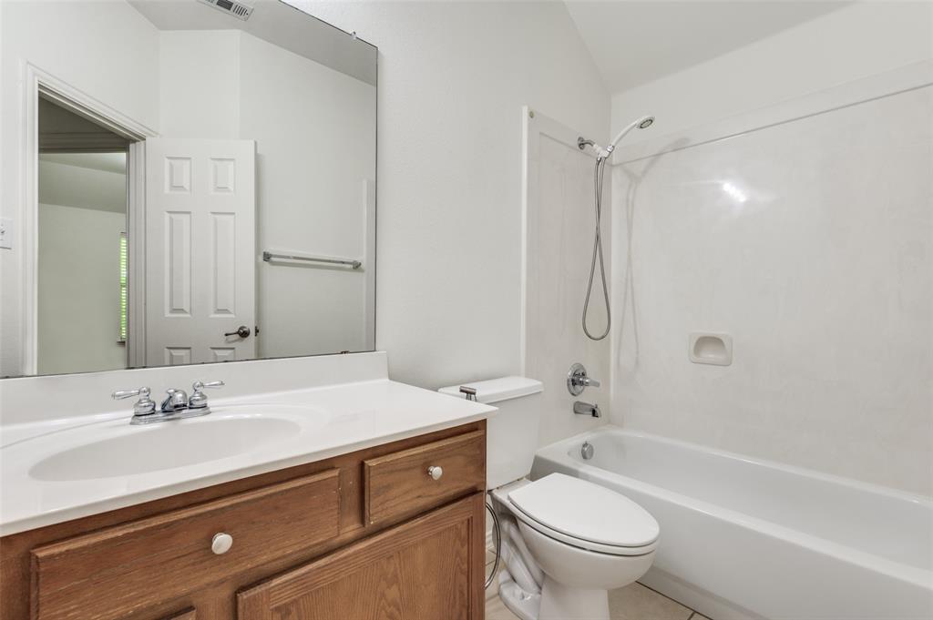 13371 Lime Ridge Drive Frisco, TX 75033 - Photo 17 of 25 The bathroom features a vanity with a white countertop and a mounted sink, a toilet, and a combination shower and bathtub