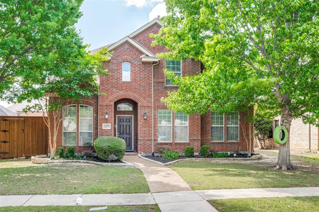 13371 Lime Ridge Drive Frisco, TX 75033 - Photo 2 of 25 The property features a brick exterior with an arched entryway and multiple windows, set amidst a well-maintained lawn with mature trees and landscaping