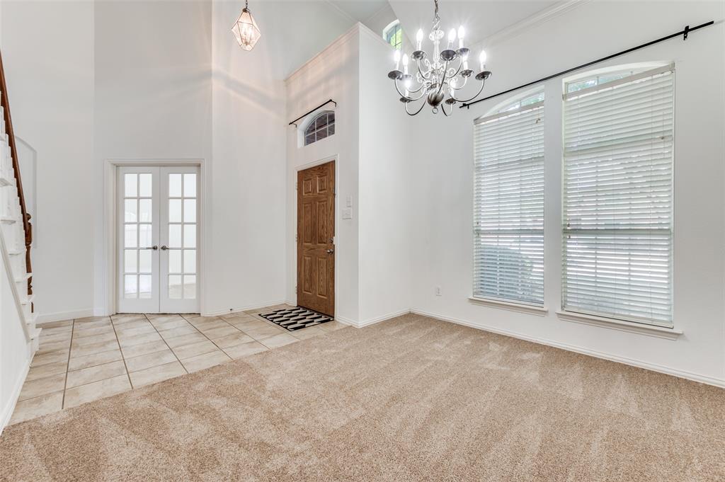 13371 Lime Ridge Drive Frisco, TX 75033 - Photo 3 of 25 Entryway featuring a wooden front door, tiled flooring, high vaulted ceilings, and a decorative chandelier