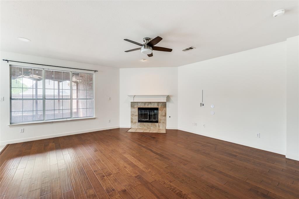 13371 Lime Ridge Drive Frisco, TX 75033 - Photo 5 of 25 Living area featuring hardwood floors, a fireplace with a stone surround, a ceiling fan, and large windows