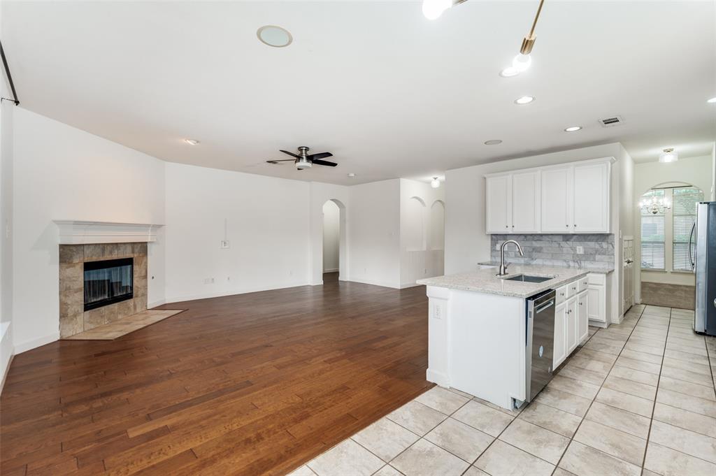 13371 Lime Ridge Drive Frisco, TX 75033 - Photo 7 of 25 The property features an open living area with hardwood flooring and a corner fireplace with a tile surround