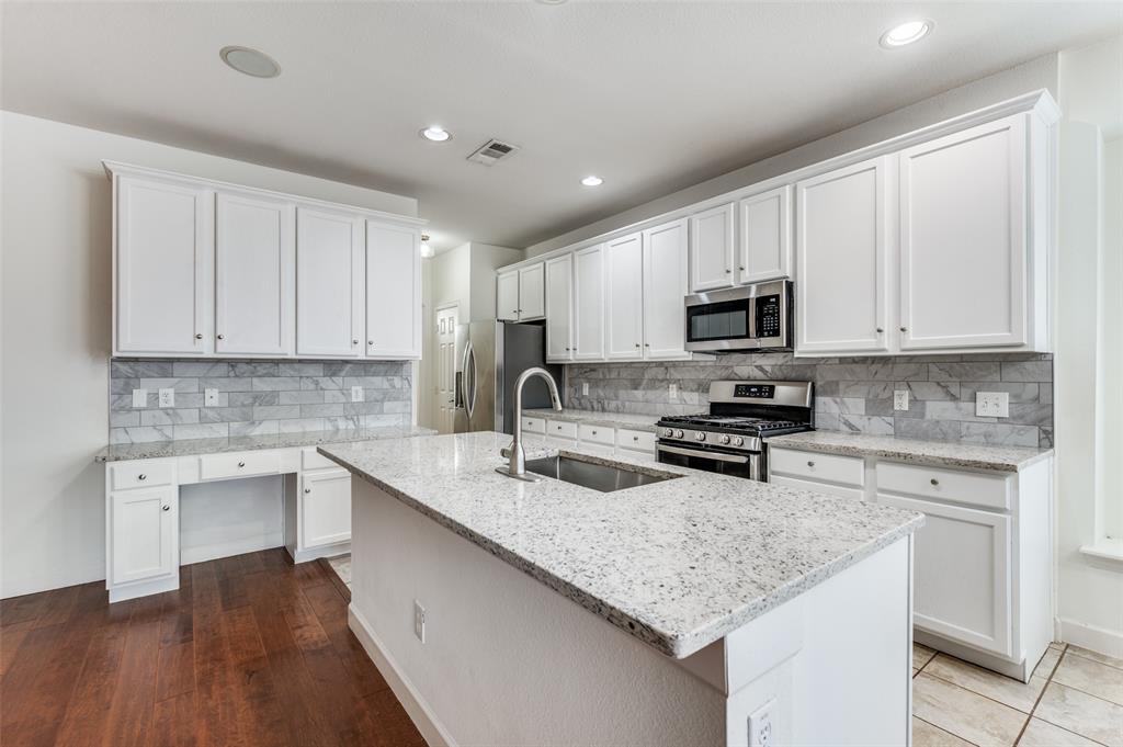 13371 Lime Ridge Drive Frisco, TX 75033 - Photo 9 of 25 The kitchen features white cabinetry, granite countertops, a tile backsplash, and stainless steel appliances