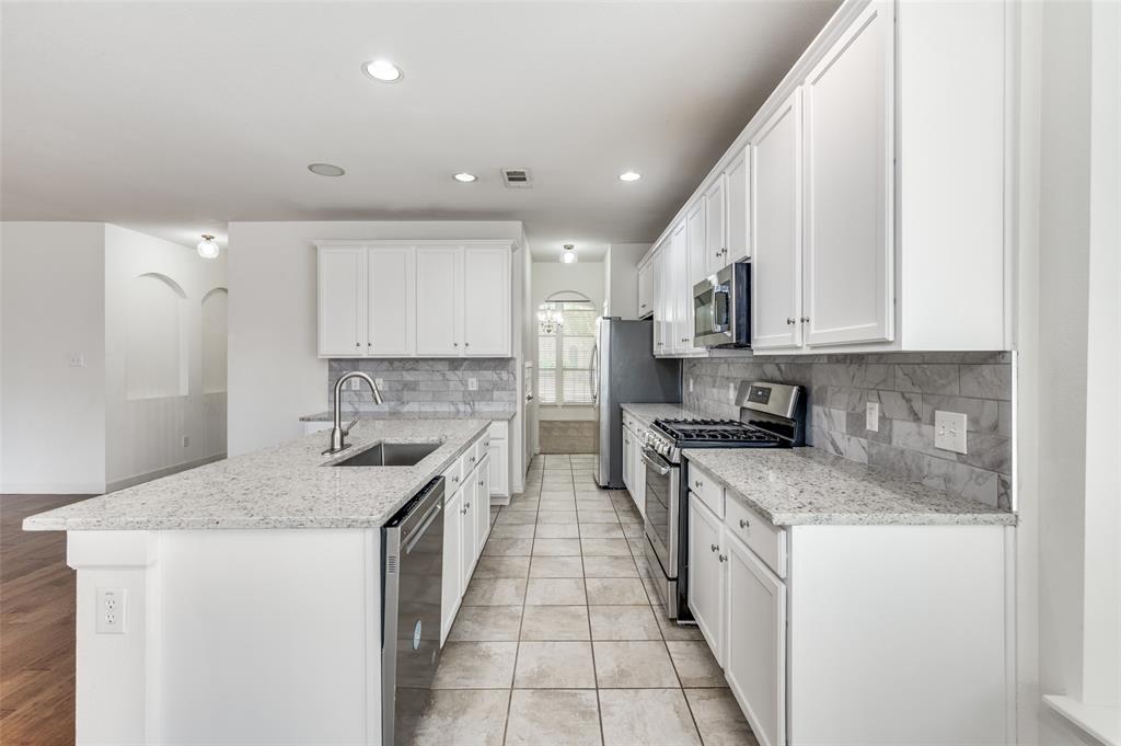 13371 Lime Ridge Drive Frisco, TX 75033 - Photo 10 of 25 The kitchen features white cabinetry, stainless steel appliances, light-colored countertops, and a subway tile backsplash