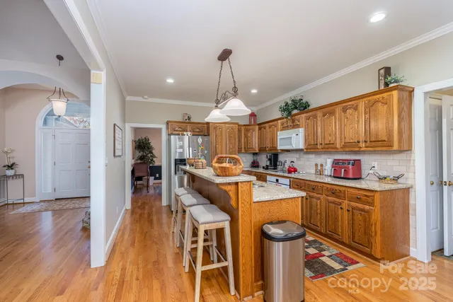 a large kitchen with stainless steel appliances kitchen island granite countertop a sink a stove and a wooden floors