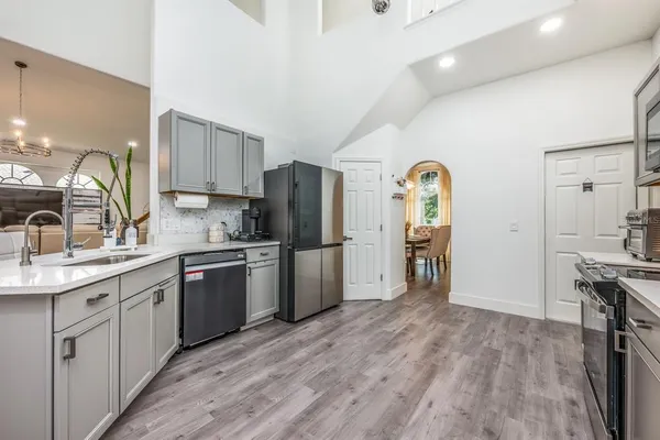 a kitchen with a refrigerator a sink dishwasher and a stove with wooden floor