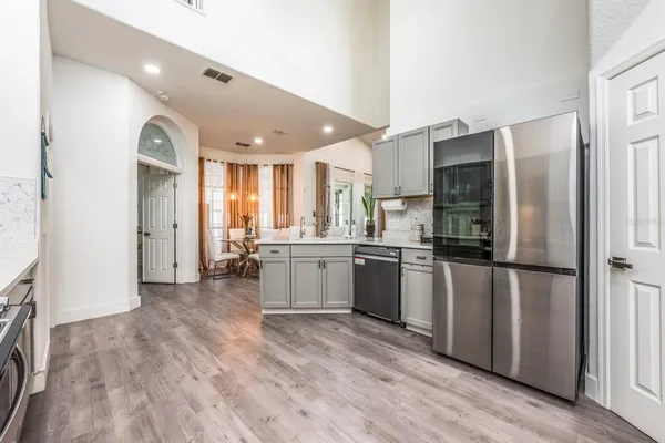 a kitchen with stainless steel appliances granite countertop a refrigerator a sink a stove and oven with wooden floor